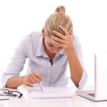 Een vrouw zit aan een bureau en werkt op haar laptop. Ze vraag zich af: Is een offerte bindend in België